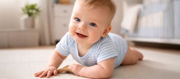 mosolygó kisbaba kúszás közben a szobában, amely a baba fejlődését és az ideális baba súly alakulását szemlélteti az első hónapokban